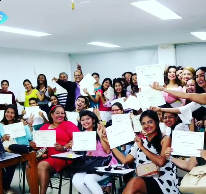 Grupo de profesionales sonriendo y mostrando sus certificados de CAIF dentro de un salón